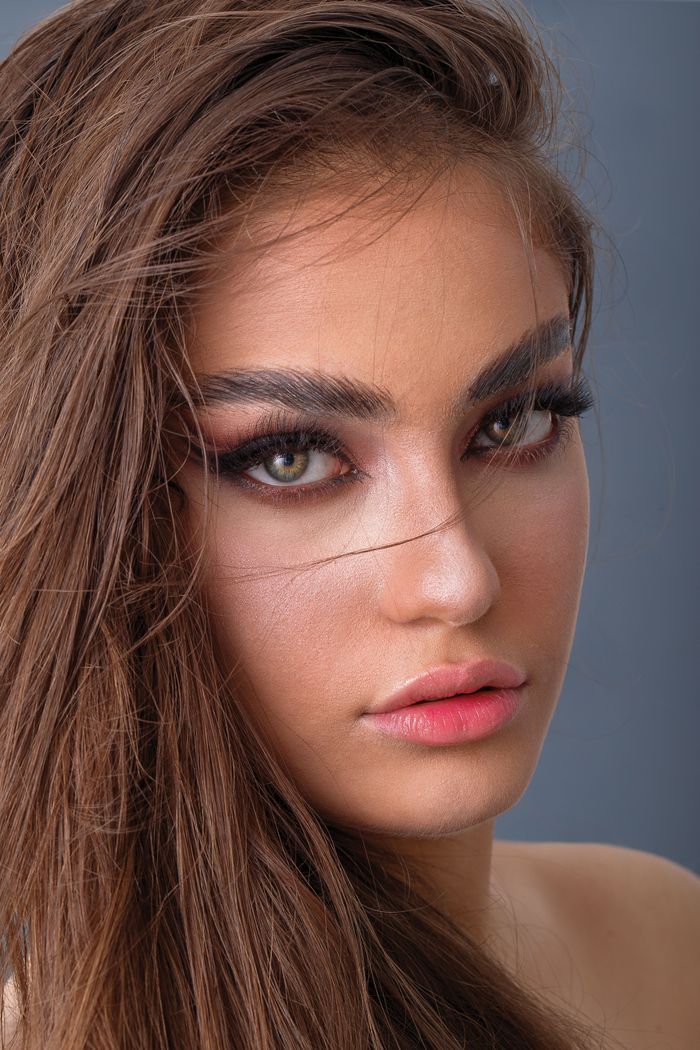 Stunning close-up portrait of a young woman with long brown hair and vibrant makeup.