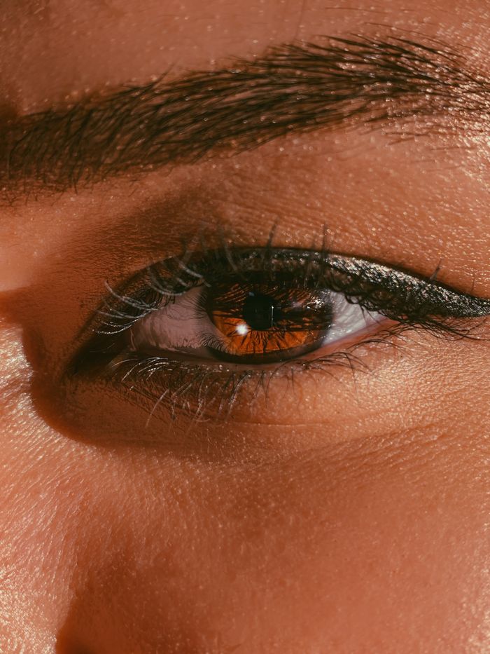 Detailed close-up of a woman's eye with brown iris and black eyeliner.