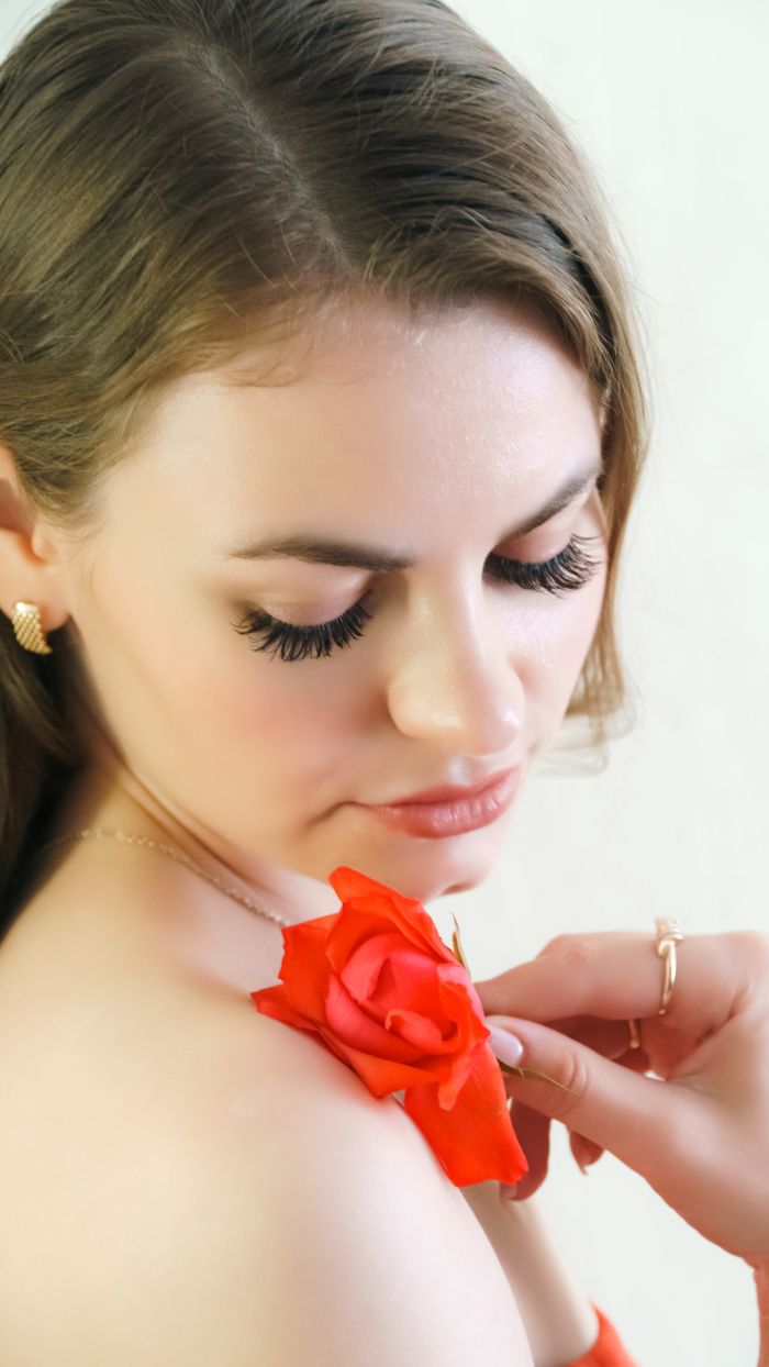 Close-up portrait of an elegant woman holding a red rose, showcasing beauty and sophistication.